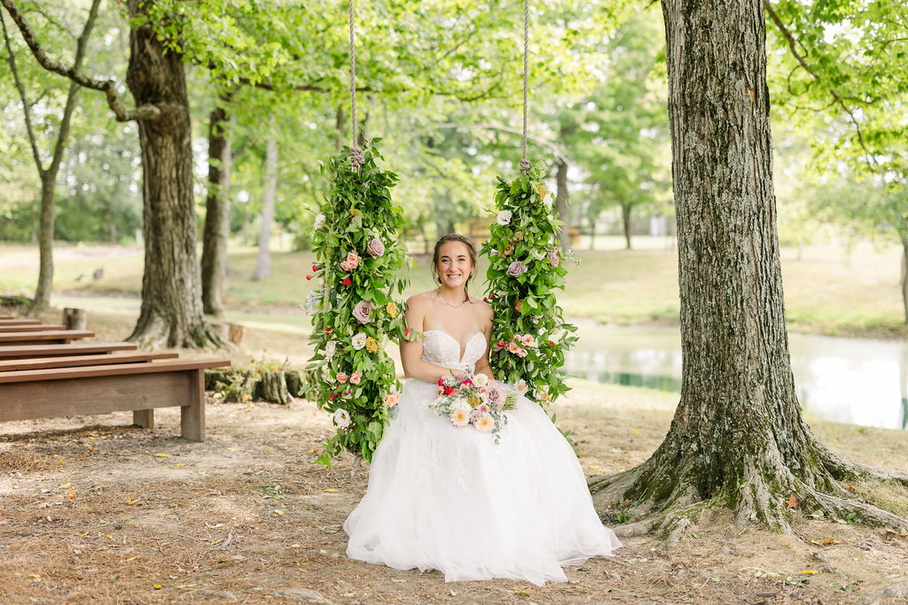 Bride sitting on swing with flowers at The Marmalade Lily